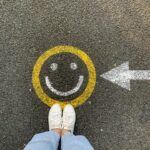 Smiley face drawn on road with a persons shoes in frame